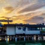 The sun sets on a stunning view of the Harbor Lights restaurant along the water-front.